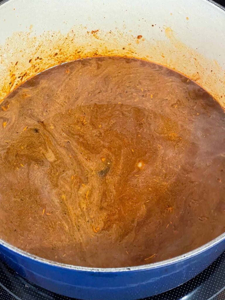 A brisket chili base cooking in a dutch oven.